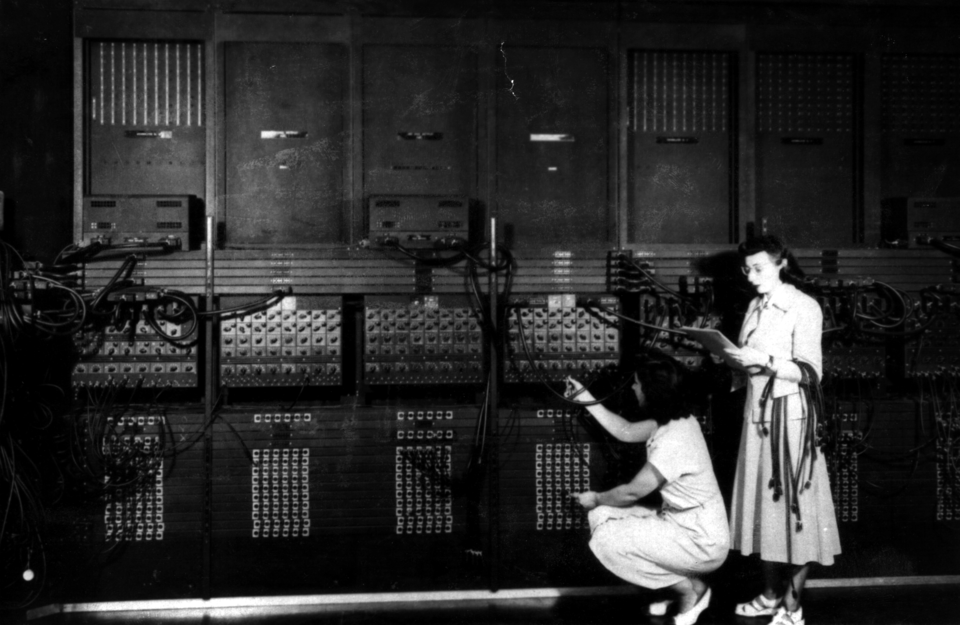 Two women programming the ENIAC computer by plugging in cables.